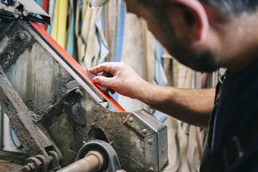 Handwerker, der in seiner Werkstatt Messer herstellt und die Klinge schärft - DGOF00785