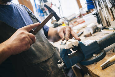 Handwerker bei der Bearbeitung eines Messers in seiner Werkstatt - DGOF00795