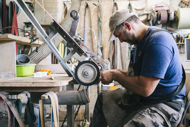 Handwerker bei der Herstellung von Messern in seiner Werkstatt - DGOF00797