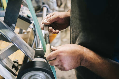 Handwerker bei der Bearbeitung eines Messers in seiner Werkstatt - DGOF00798