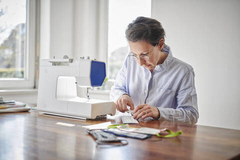 Woman sewing face masks at home stock photo