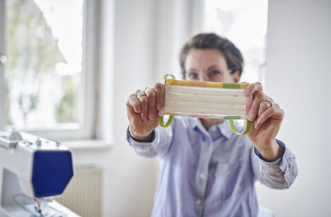 Frau zeigt Gesichtsmaske, die sie zu Hause genäht hat, lizenzfreies Stockfoto