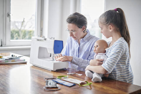 Mother sewing face masks for her daughter and her doll stock photo