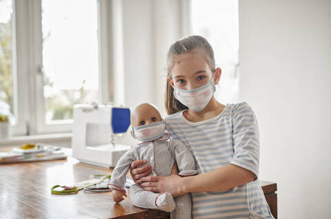 Kleines Mädchen und ihre Puppe, mit selbstgemachten Gesichtsmasken, lizenzfreies Stockfoto