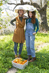 Two women with their harvest of organic oranges and lemons - VSMF00043