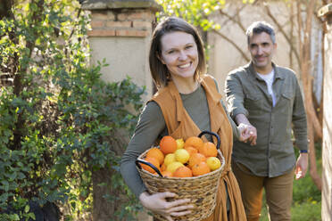 Glückliches Paar hält einen Korb mit Zitronen und Orangen - VSMF00048