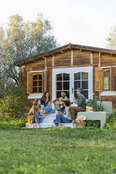 Friends playing music on the guitar and drinking wine outside a cabin in the countryside - VSMF00052