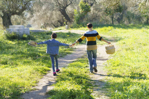 Mutter und Tochter gehen Hand in Hand auf einem ländlichen Weg, lizenzfreies Stockfoto