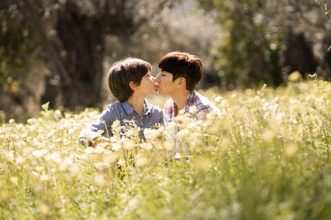 Mutter und Tochter küssen sich in einem Feld voller Wildblumen, lizenzfreies Stockfoto