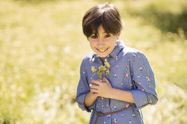Portrait of happy girl holding wildflowers - VSMF00098