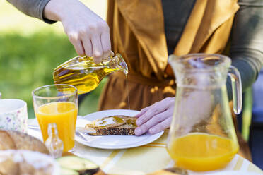 Close-up og woman pouring olive oil on bread - VSMF00102