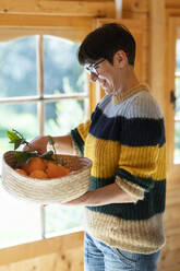 Woman with basket of oranges in a wooden cabin - VSMF00106