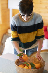 Woman with basket of oranges in a wooden cabin - VSMF00107