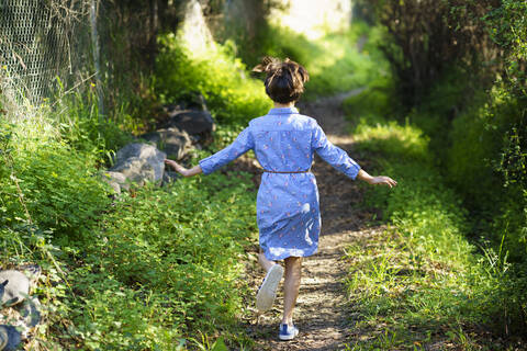 Mädchen läuft auf einem Feldweg, Rückansicht, lizenzfreies Stockfoto