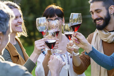 Group of friends toasting with red wine on their getaway in the countryside - VSMF00156