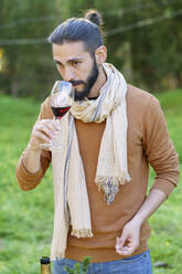 Portrait of young man tasting red wine in the countryside - VSMF00157