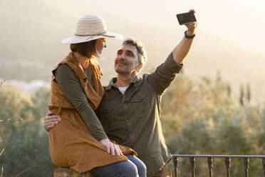 Paar nimmt Selfie mit Smartphone während des Sonnenuntergangs auf dem Lande - VSMF00177