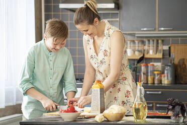 Mutter und Sohn schneiden Tomaten in der Küche - VPIF02213