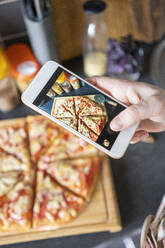 Frauenhand, die eine selbstgemachte Pizza mit dem Smartphone fotografiert - VPIF02229