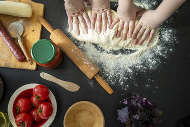 Hands of mother and son kneeling dough together - VPIF02237