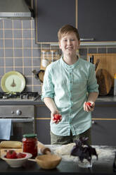 Portrait of smiling boy juggling with tomatoes in the kitchen - VPIF02242