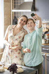 Mutter und Sohn machen Selfie mit Smartphone in der Küche - VPIF02245