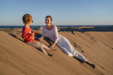 Happy mother and daughter relaxing in sand dunes, Gran Canaria, Spain - DIGF09536