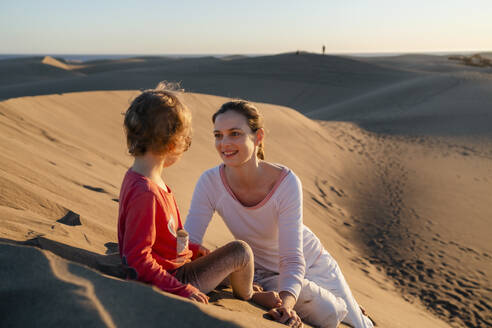 Happy mother and daughter relaxing in sand dunes, Gran Canaria, Spain - DIGF09537