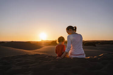 Mutter und Tochter sitzen bei Sonnenuntergang in den Sanddünen, Gran Canaria, Spanien - DIGF09541