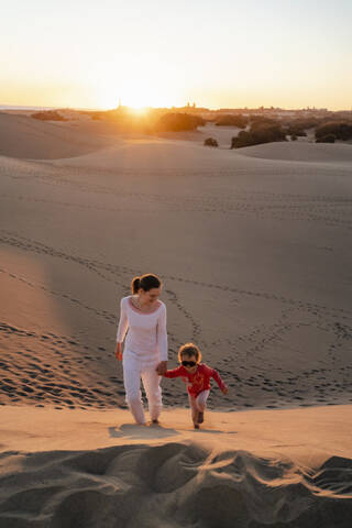 Mother and daughter walking up sand dune at sunset, Gran Canaria, Spain stock photo