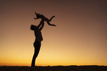 Father playing with daughter on sand dune at sunset, Gran Canaria, Spain - DIGF09557