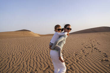 Mutter trägt Tochter huckepack in Sanddünen, Gran Canaria, Spanien - DIGF09580