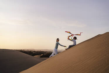 Mother and daughter flying kite in sand dunes, Gran Canaria, Spain - DIGF09598