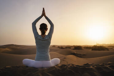Woman practicing yoga in sand dunes at sunset, Gran Canaria, Spain - DIGF09604