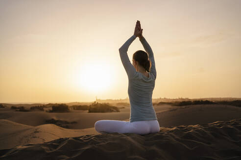 Woman practicing yoga in sand dunes at sunset, Gran Canaria, Spain - DIGF09605