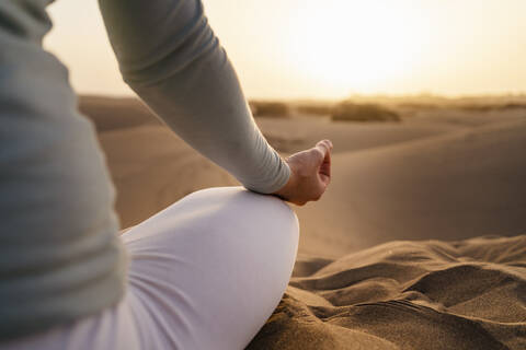 Close-up of woman practicing yoga in sand dunes at sunset, Gran Canaria, Spain stock photo