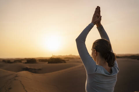 Frau übt Yoga in Sanddünen bei Sonnenuntergang, Gran Canaria, Spanien, lizenzfreies Stockfoto