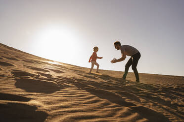 Vater und Tochter spielen in einer Sanddüne bei Sonnenuntergang, Gran Canaria, Spanien - DIGF09615