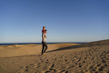 Father carrying daughter on shouldres in sand dunes, Gran Canaria, Spain - DIGF09618