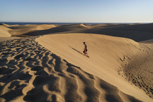 Father and daughter walking up sand dune, Gran Canaria, Spain - DIGF09622