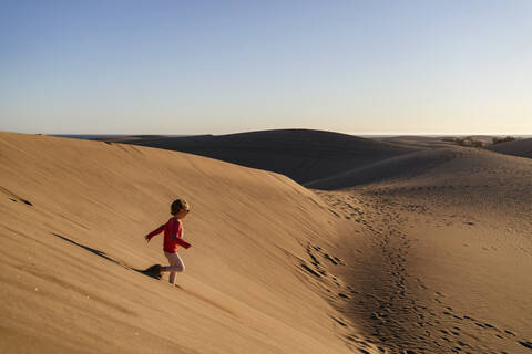 Girl running down sand dune, Gran Canaria, Spain stock photo