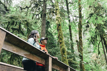 A young couple enjoys a hike in a forest in the Pacific Northwest. - CAVF78990