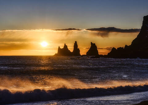 Island, Silhouetten von Reynisdrangar Meeresklippen bei stimmungsvollem Sonnenuntergang, lizenzfreies Stockfoto