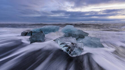 Iceland, Ice chunks lying at shore of Jokulsarlon at dusk - TOVF00167