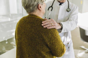 Doctor holding shoulder of senior patient in his practice - MFF05424