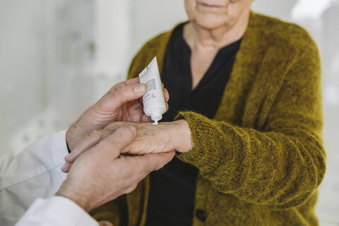 Doctor putting ointment on hand of senior patient stock photo