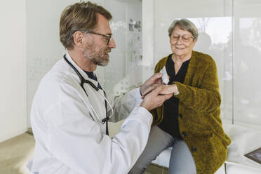 Arzt trägt Salbe auf die Hand eines älteren Patienten auf - MFF05449