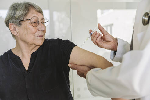 Doctor injecting vaccine into senior patient’s arm - MFF05450