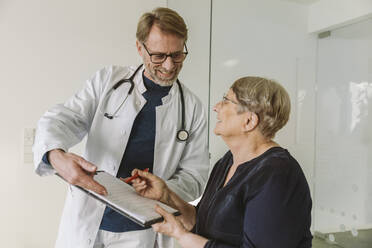 Arzt hilft älterem Patienten beim Ausfüllen eines Dokuments - MFF05454