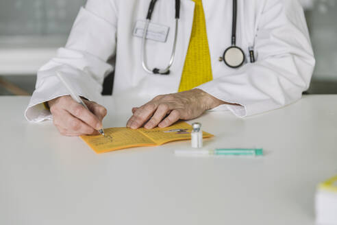 Doctor filling out immunization card - MFF05486